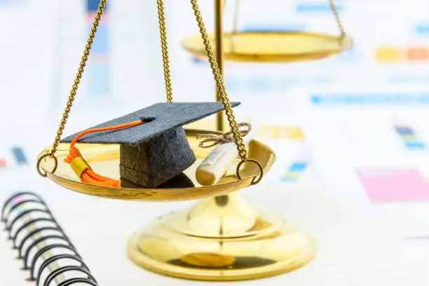 Photo of Graduate study abroad program concept : Graduation cap on a balance scale of justice and a certificate / diploma. Graduate study abroad program is a program that accept students from foreign countries