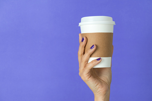 Paper cup of takeaway coffee in the hand.