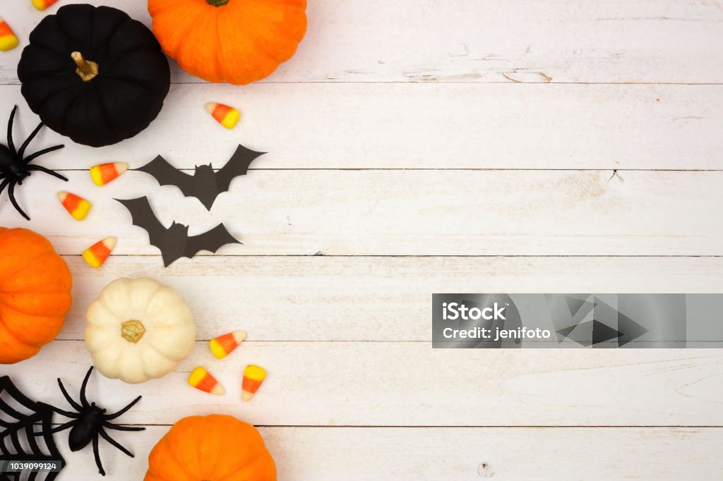 Black, orange and white Halloween side border over white wood Halloween side border with black, orange and white decor and candy over a white wood background. Top view with copy space. Halloween Stock Photo