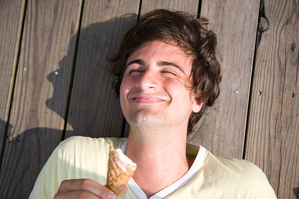 man lying on pier eating an ice cream - 4397 foto e immagini stock