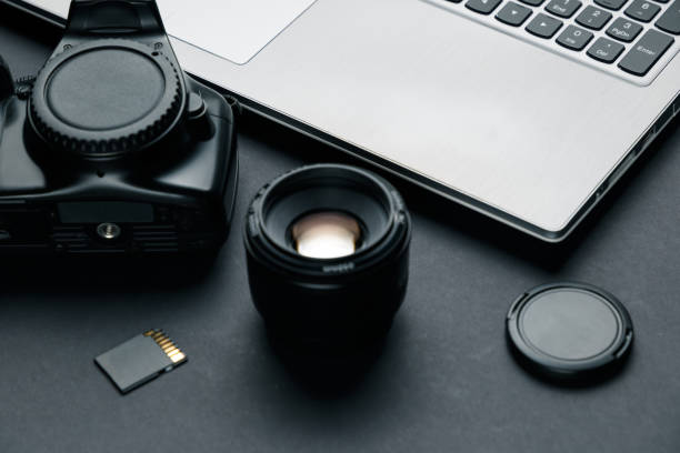 istock Work space on black table of photographer. Minimal workspace with Laptop, camera and lens copy space on dark background. Modern and elegant. 1039158806