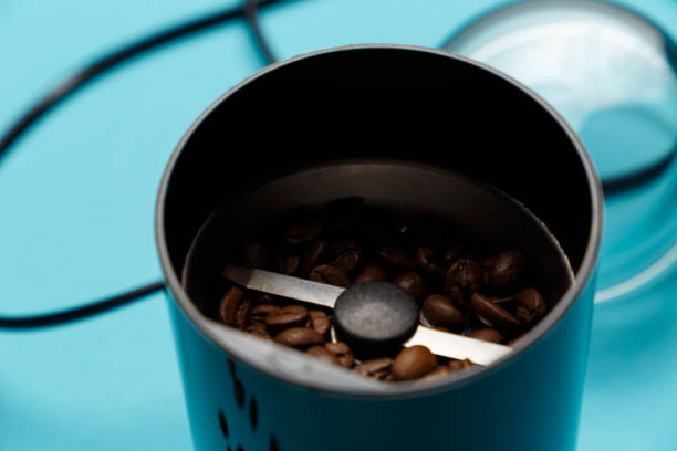 istock Electric coffee grinder with roasted coffee beans on the kitchen table with blue tabletop. Close-up 1039159916