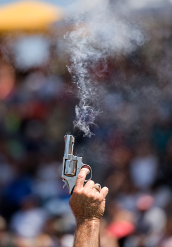A starter's pistol fires into the air to signal the start of a race.