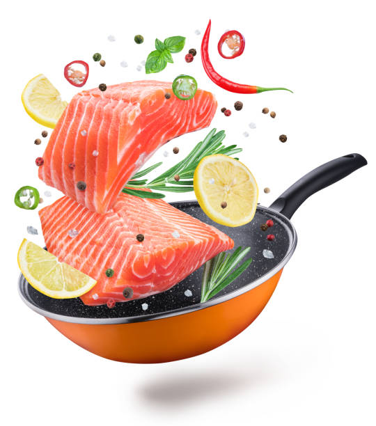 Flying salmon steaks and spices over a frying pan.