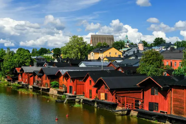 View of the picturesque river embankment in the old Finnish town of Porvoo with traditional red wooden warehouses.