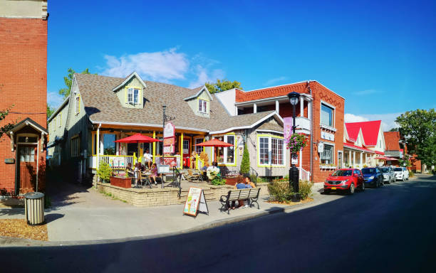 Sainte-Anne-de-Bellevue street scene panorama featuring an ice cream shop.  Photographed on a P20Pro mobile phone during a Summer late afternoon. The street is lined with restaurants, shops and several people can be seen enjoying the sunny afternoon.