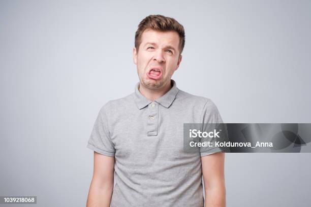 Closeup Portrait Of Funny Angry Young Bully Man Sticking His Tongue Out At You Camera Gesture Stock Photo - Download Image Now