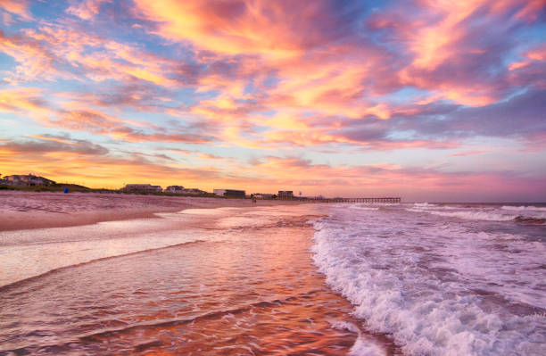 The sun sets on the surf and sand in Wrightsville Beach, NC.