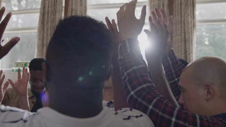 Men praying with arms raised in mens group