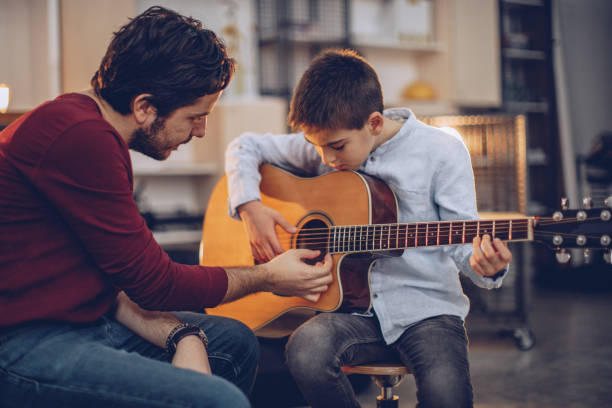 jeune garçon enseigner à jouer de la guitare - guitar child music learning photos et images de collection