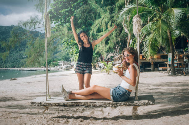 istock Two beautiful girlfriend enjoy a swing and drink coconut 1039312136