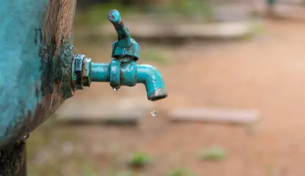 Photo of A faucet with a water drop / Water consumption concept
