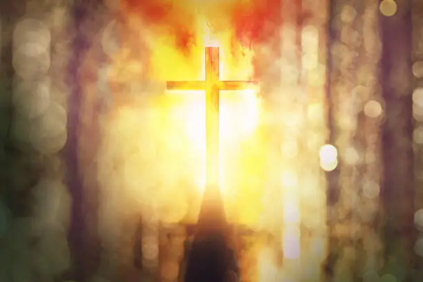 Photo of silhouette of burning cross with rays of sunlight background