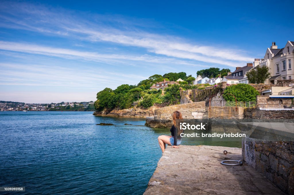 Woman enjoying view of Kinsale Harbor from Summer Cove in Ireland A female Asian tourist in her 40s is soaking up the Summer Irish sun along the coastline of Kinsale in Country Cork. She's enjoying the affluent neighborhood of Summer Cove. Ireland Stock Photo
