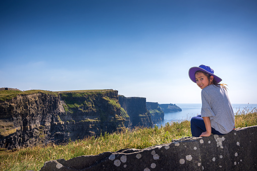 An 8 year old Eurasian girl is enjoying the spectacular view of the Cliffs of Moher, which are 200m high cliffs located at the southwestern edge of the Burren region in County Clare, Ireland.