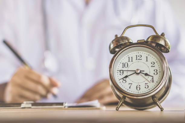 istock alarm clock on desk with blur doctor working in office background 1039397980
