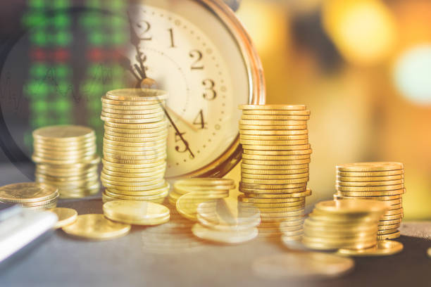 istock double exposure stack of coins ,clock and stock market screen 1039398040
