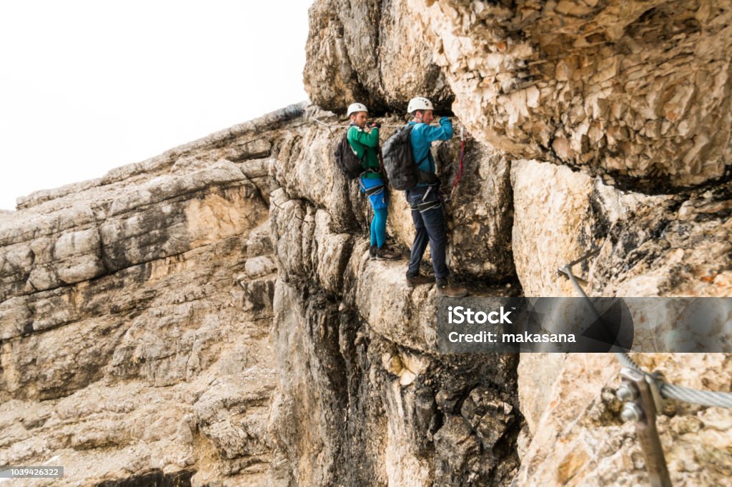 zwei junge attraktive männliche Bergsteiger auf sehr exponierten Klettersteig in den Dolomiten Italien - Lizenzfrei Klettersteig Stock-Foto