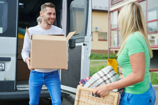 istock Cheerful excited young man in jeans passing moving box to wife while they unloading minivan near new house 1039433916