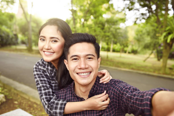 Two asian lovers making a selfie on phone Two asian lovers making a selfie on phone at the park happy malay couple stock pictures, royalty-free photos & images