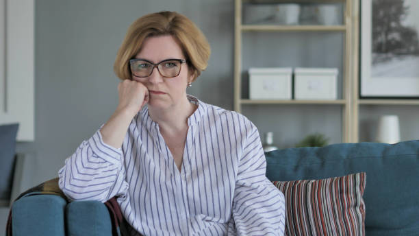 istock Sad Old Woman Sitting on Sofa 1039462054