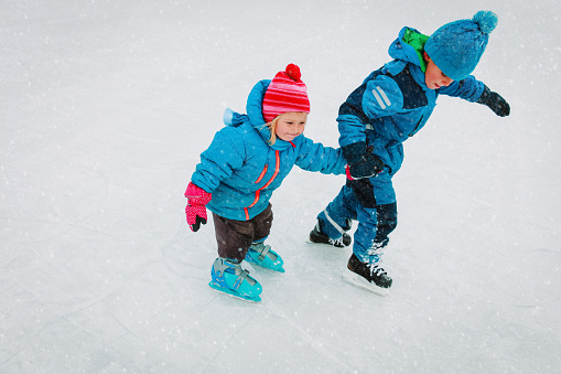 little boy and girl skating together in winter snow, kids winter sport