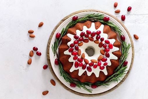 Christmas festive pound cake decorated with cranberries almonds and rosemary twigs, view from above