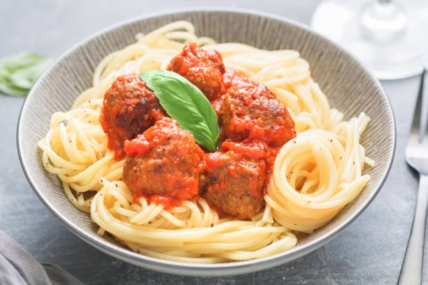 istock Beef meatballs in tomato sauce with Italian spaghetti and fresh basil leaf on a dinner table. Simply homemade recipe, close up. 1039495032
