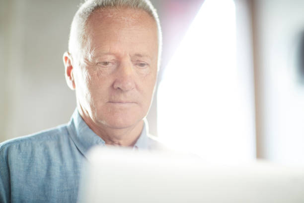 istock Serious busy handsome senior male entrepreneur focused on project analyzing information on laptop while examining file 1039504396
