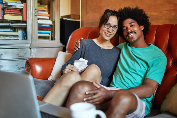 istock Happy man with arm around woman sitting on sofa 1039506576
