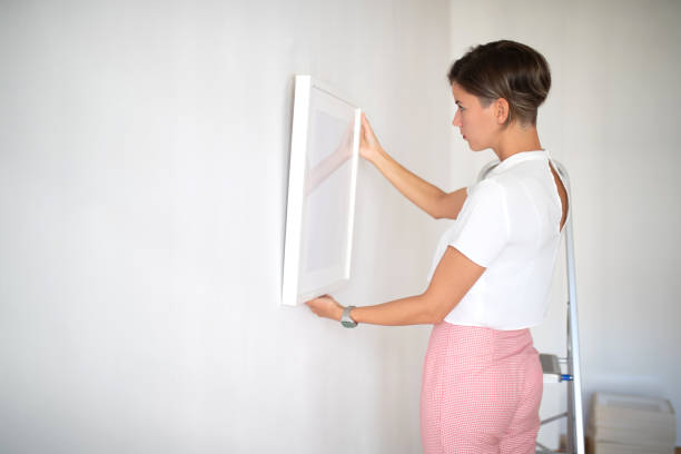 istock Woman positioning painting on the wall 1039513806
