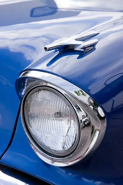 Oldsmobile, headlight on blue car.