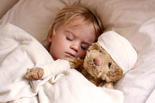 boy and teddybear in bed stock photo