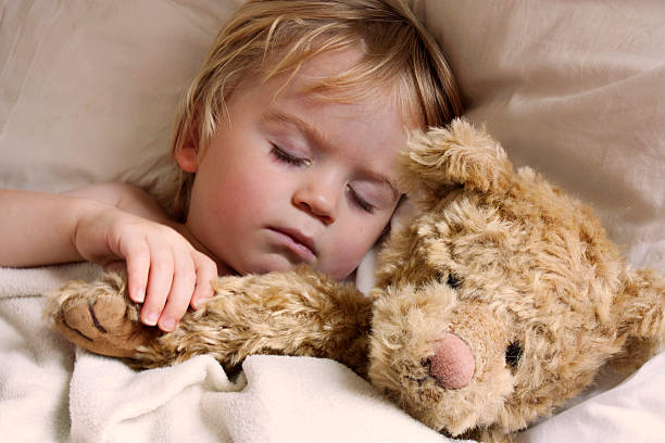 baby toddler asleep with teddy bear stock photo