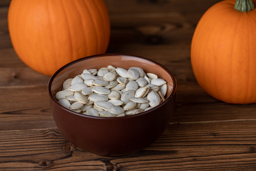 Fresh orange pumpkins and pimpkin seeds close-up on wooden background