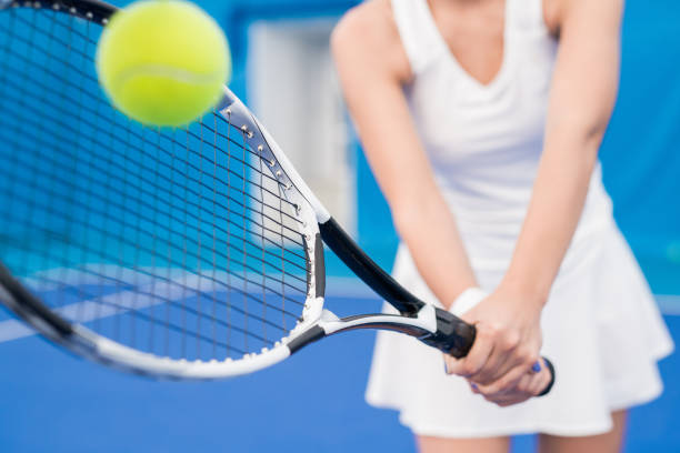 Closeup of unrecognizable tennis player hitting ball with racket while playing sports in indoor court, copy space
