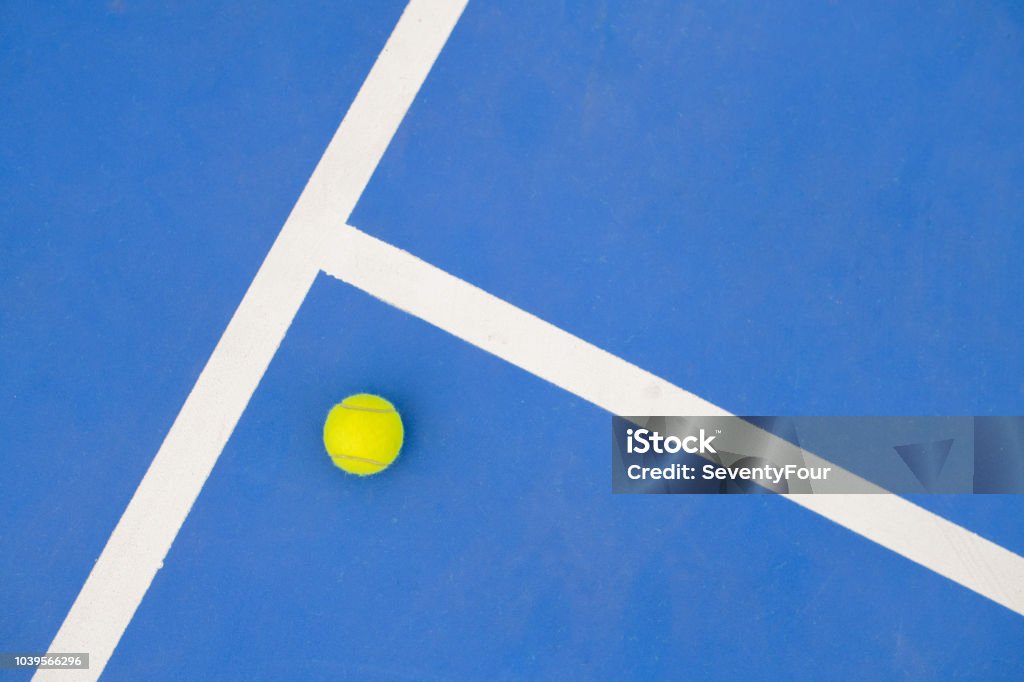 Graphic Tennis Background Graphic sports background of yellow tennis ball laying on blue floor in court, copy space Tennis Stock Photo