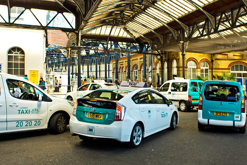 The taxi rank outside Brighton train station with white taxis lined up to pick up passengers.