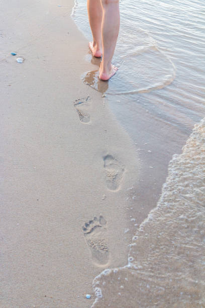 istock Lonely girl walking on the sand with footprints 1039573016