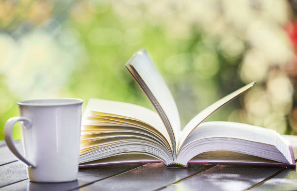 istock Open book and coffee mug on table in sunny garden 1039573050