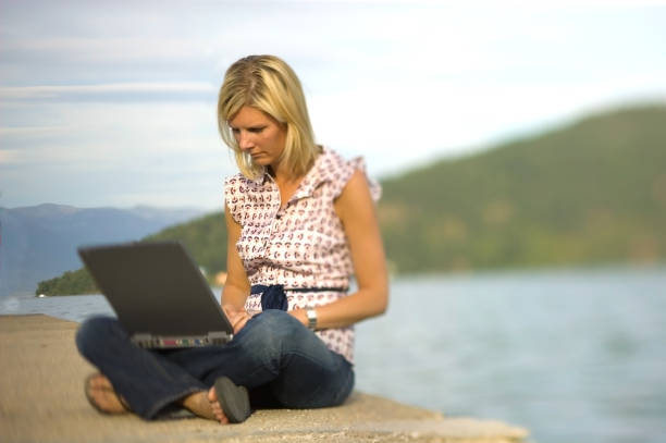 istock Blonde at lake using laptop 103957800