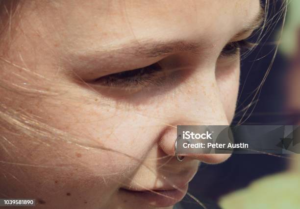 A Young Woman With A Fresh Nose Piercing Looking Off Camera Stock Photo - Download Image Now