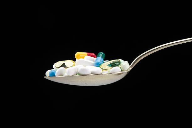 Spoon full of pills and capsules stock photo