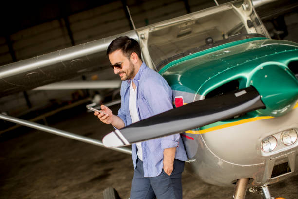 istock Handsome young pilot checking airplane in the hangar and using mobile phone 1039592204