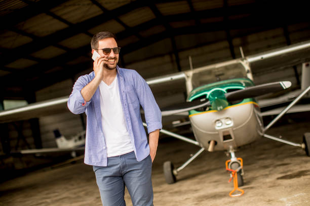 istock Handsome young pilot checking airplane in the hangar and using mobile phone 1039592328