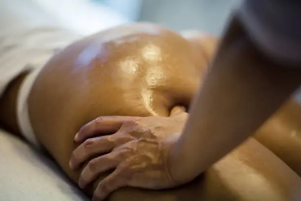 Perfect body. The masseur makes Anti-cellulite massage on the buttock and thighs of the patient. Close up.
