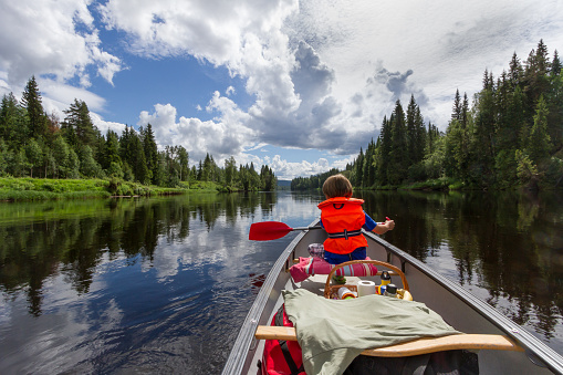 Canoa de niño remando en el río en hermosa norte de Suecia photo