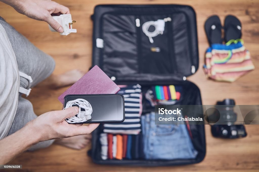 Preparing for trip Preparing for trip. Young man packing clothing for vacation, flip flop, camera and other things on hardwood floor. Travel Stock Photo