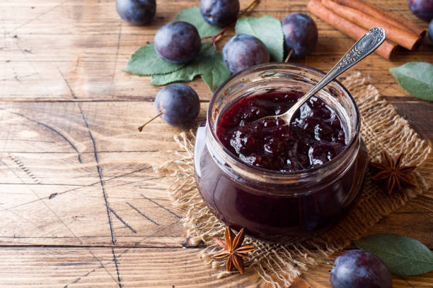 istock Plum jam in a glass jar. Fresh plum fruit on a wooden table. 1039626318