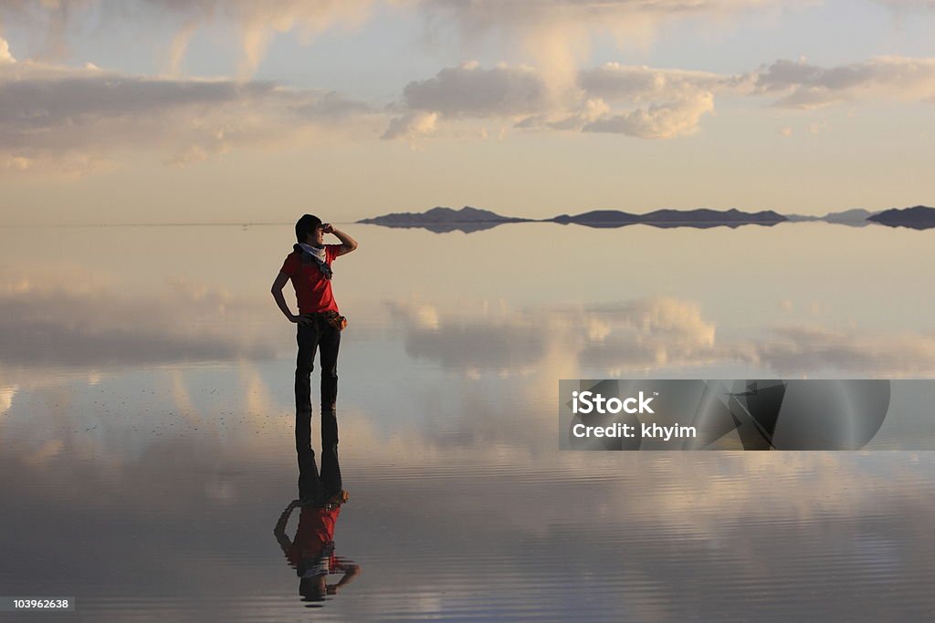 A man watching the sunset at Uyuni salt flat The perfect reflection of gorgeous sunset at Uyuni Salt Flat, Bolivia Salt Flat Stock Photo